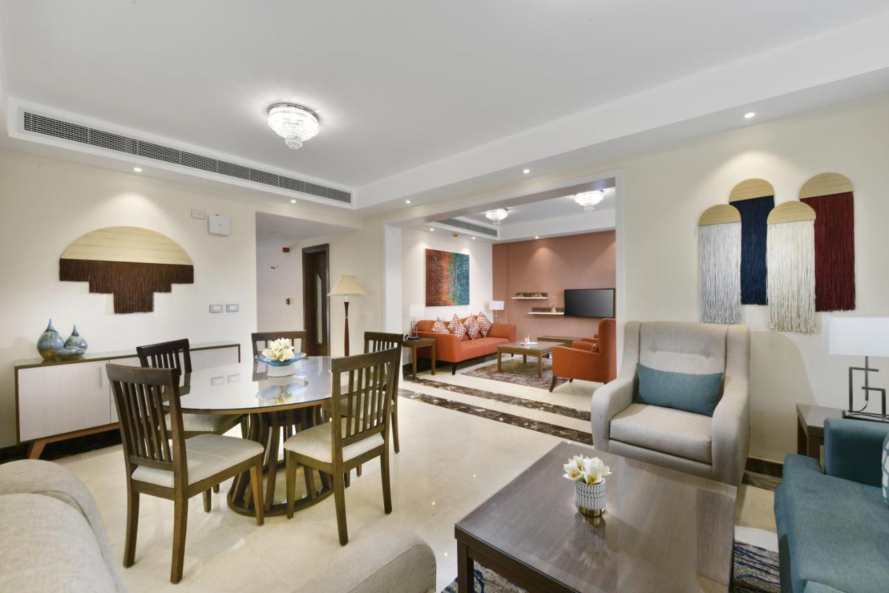 Tolip Resort El Galala Majestic Айн Сохна Екстериор снимка The photo shows a modern living room space that is elegantly designed. It features a seating area with a comfortable sofa and armchairs, complemented by a decorative coffee table. There is a dining table with several wooden chairs, providing a cozy a