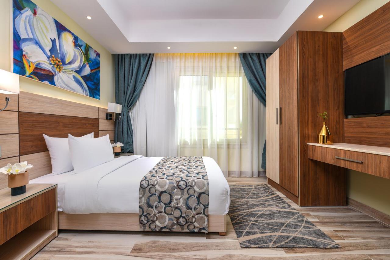 Tolip Resort El Galala Majestic Айн Сохна Екстериор снимка The photo shows a well-designed hotel room. It features a comfortable bed with a decorative bedspread and two pillows. There are soft curtains framing a window that lets in natural light. On one side, there is a colorful piece of artwork hanging on t