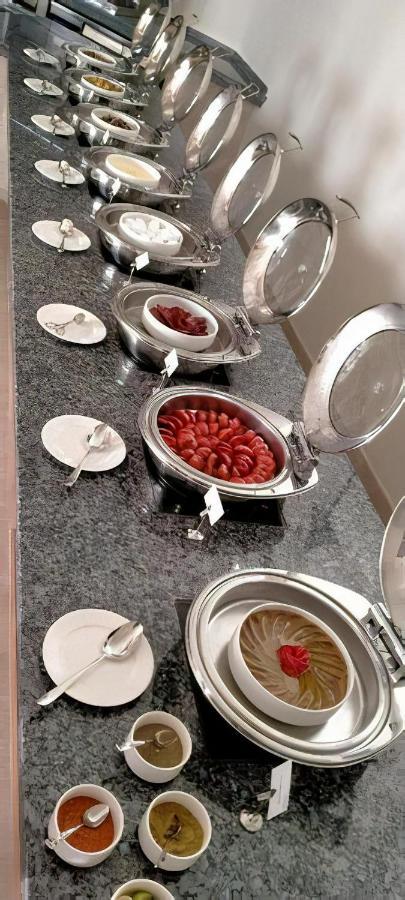 Tolip Resort El Galala Majestic Айн Сохна Екстериор снимка The photo shows a buffet setup featuring multiple metal serving trays on a dark granite countertop. One tray contains circular slices of food, possibly sausages or a similar dish, while another bowl holds what appears to be red food items, though it'