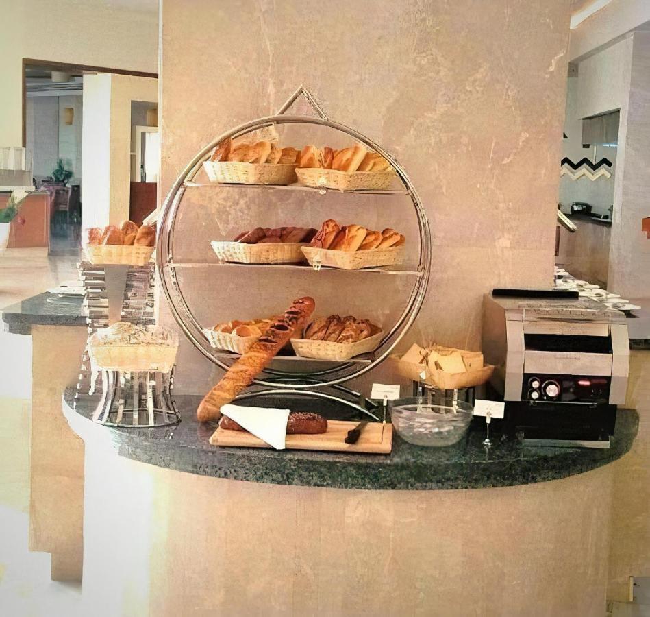 Tolip Resort El Galala Majestic Айн Сохна Екстериор снимка The photo shows a display of various types of bread and pastries arranged on a countertop. There are several baskets stacked on a circular stand, filled with different baked goods like croissants and rolls. A long baguette is placed horizontally on a