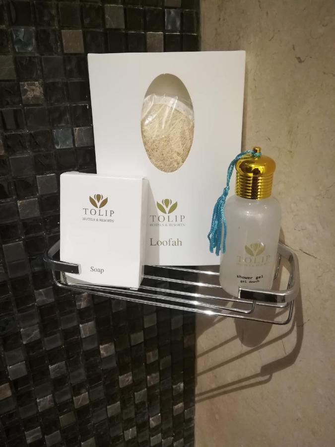 Tolip Resort El Galala Majestic Айн Сохна Екстериор снимка The photo shows a small metal shelf containing three items related to personal care. 

1. **Soap**: A white box labeled "TOLIP" with the word "Soap" visible on the front.
2. **Loofah**: A package with the same "TOLIP" branding, containing loofah.
3. 